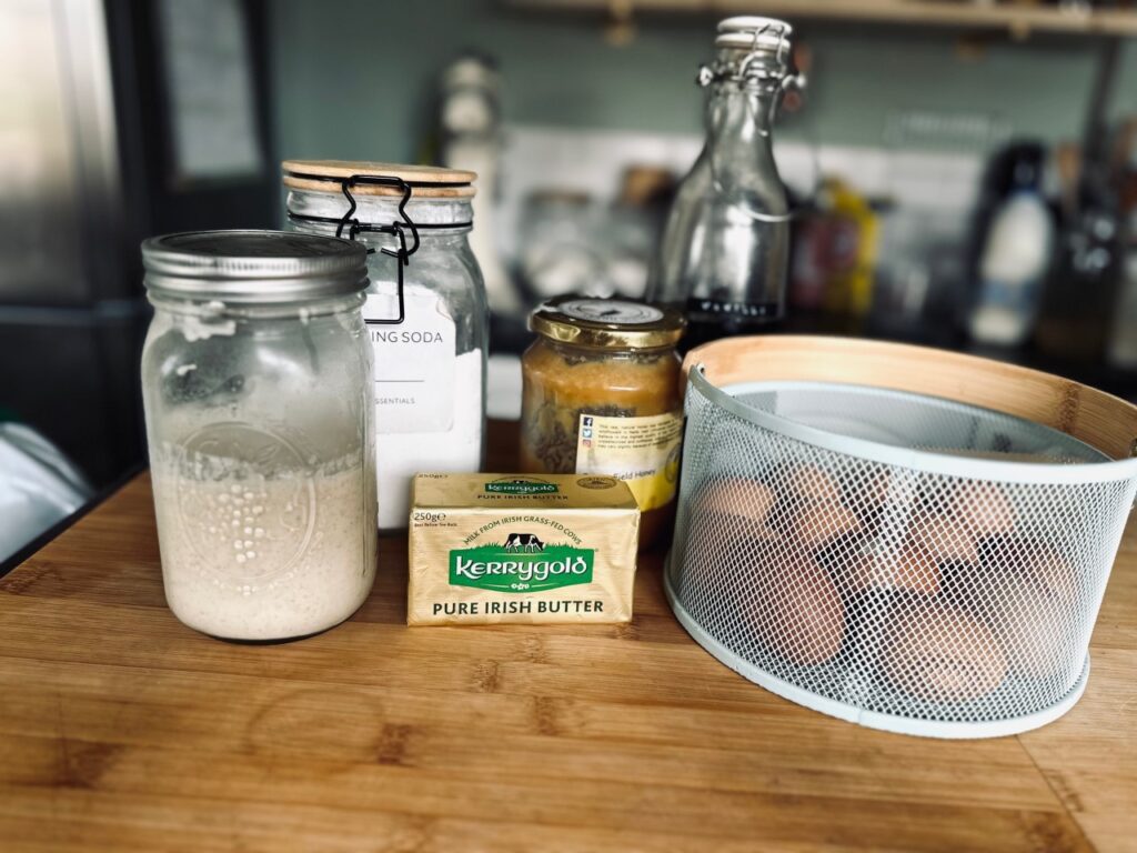 Ingredients for Sourdough waffles in jars and bottles on a wooden work surface