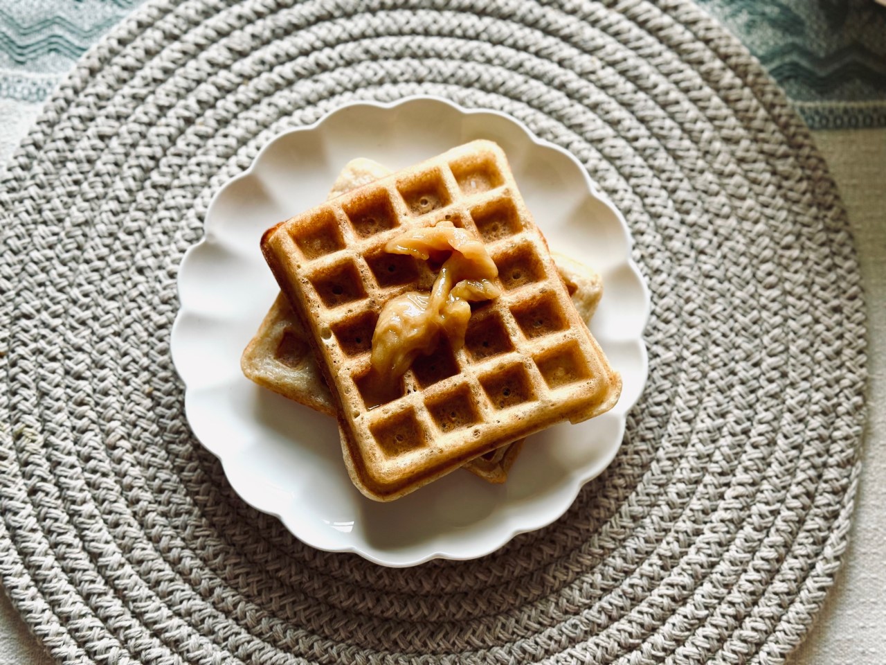 A plate of honey topped sourdough waffles on a spiral placemat