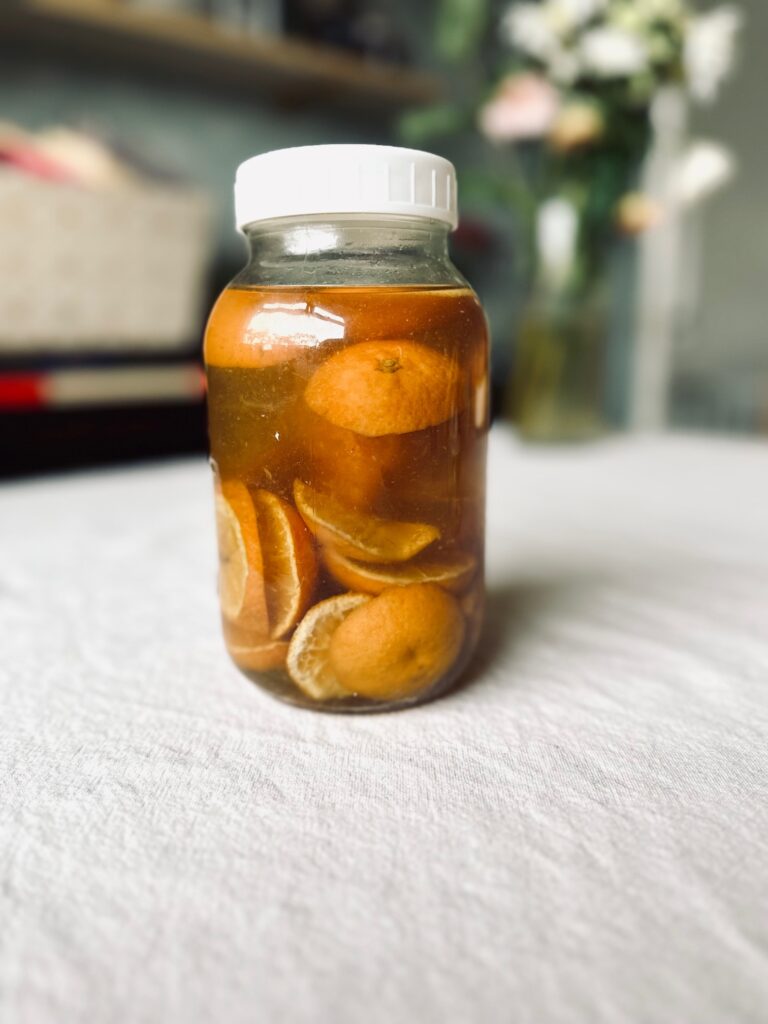 A jar of oranges in vinegar on a white tablecloth