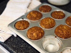 Half tray of muffins next to a tea towel