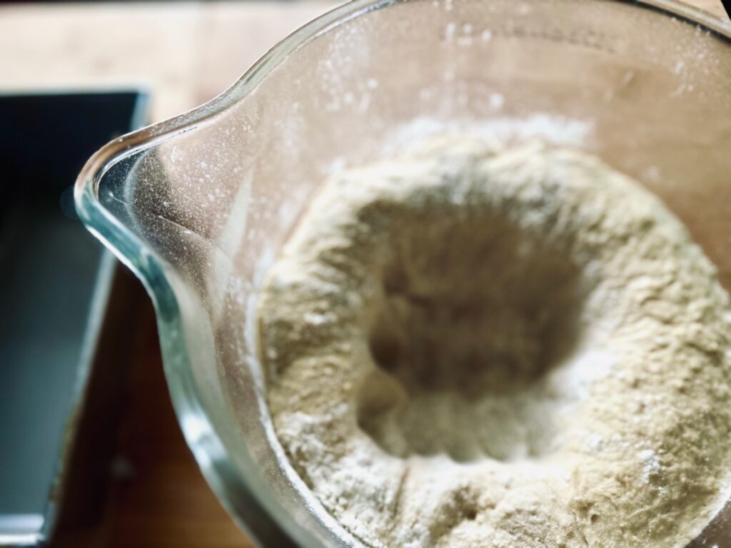 A top view of a bowl of dough punched down