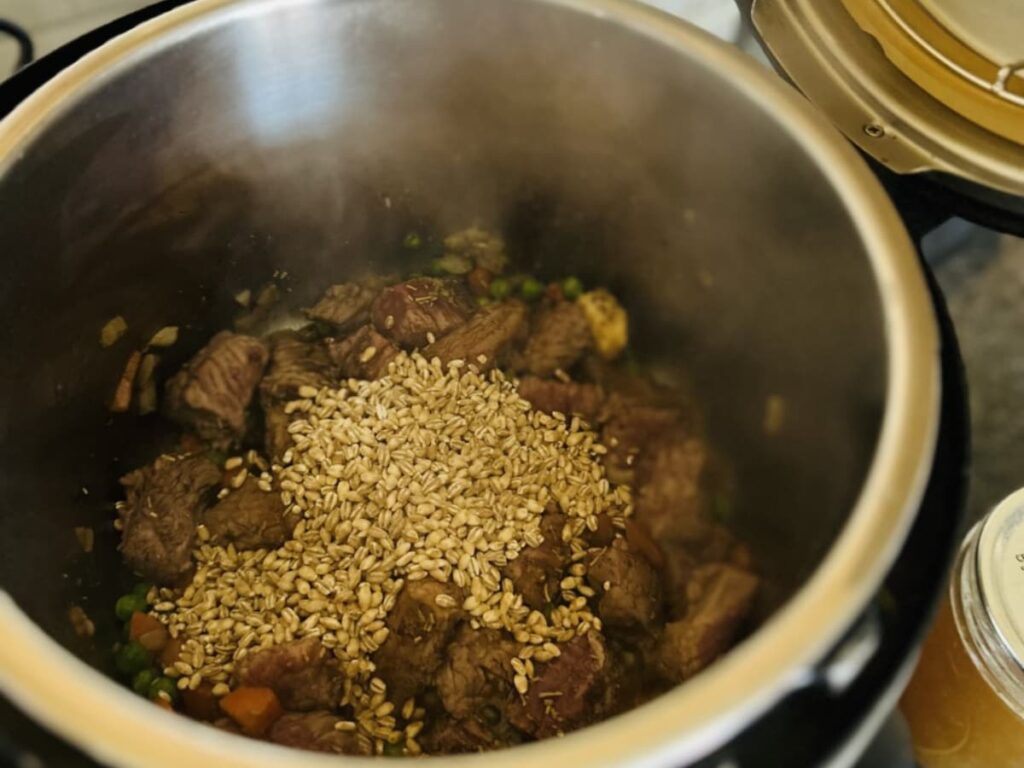 An instant pot with meat and dry barley