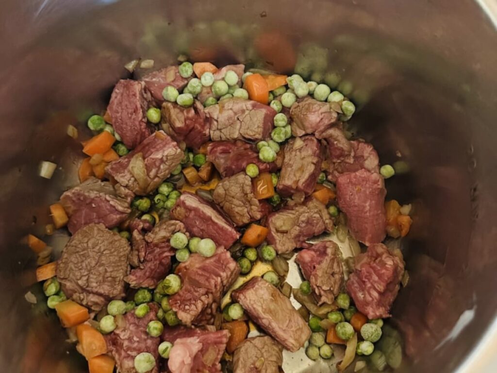 Meat browning in an instant pot with vegetables