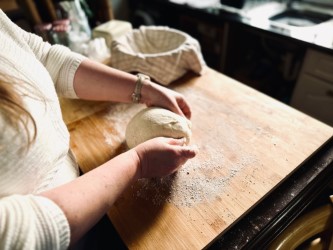 A woman kneading bread dough on a wooden board