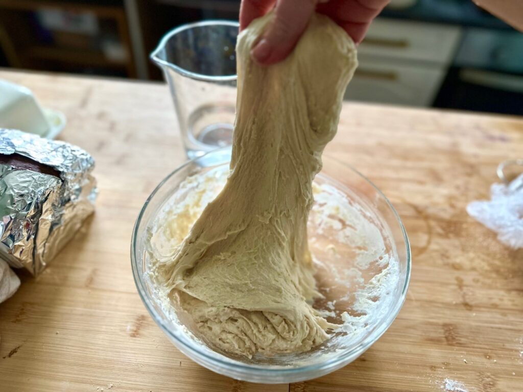 A hand stretching dough upwards