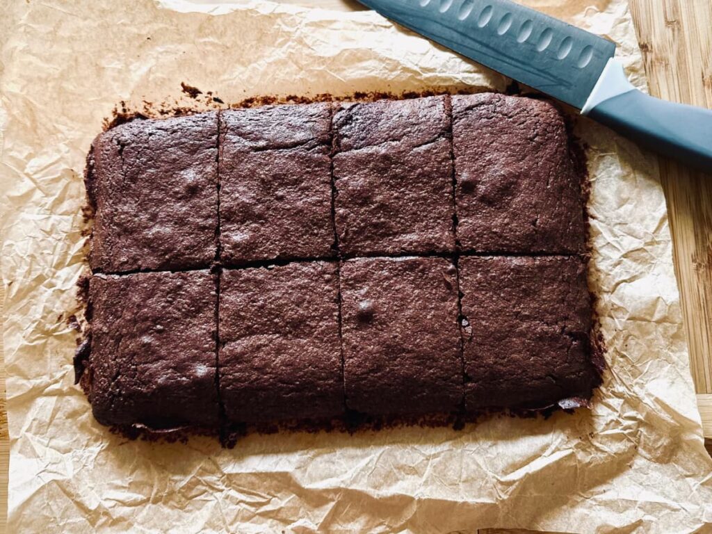 Sliced sourdough brownies on a board with a knife
