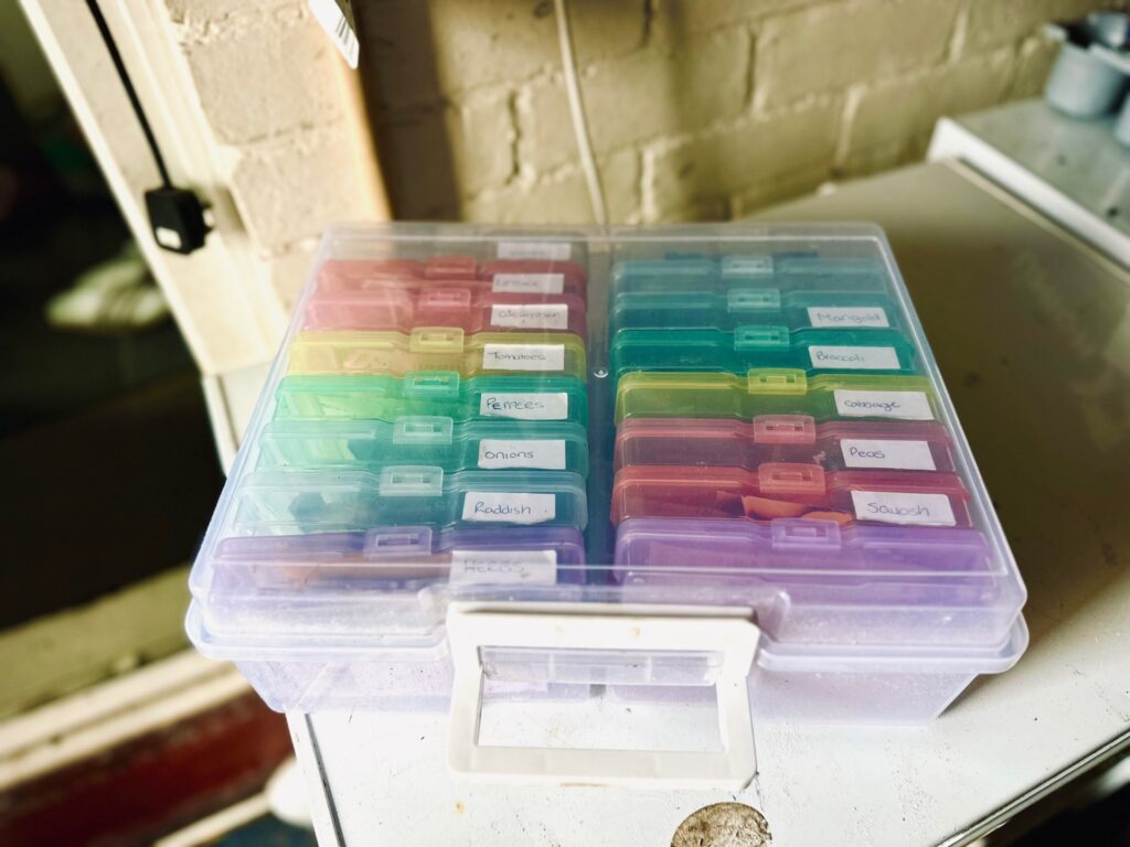 A box full of coloured cassette containers full of seed packets