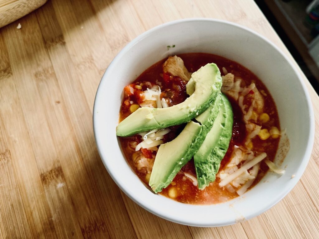 A taco bowl topped with avocado on a wooden board