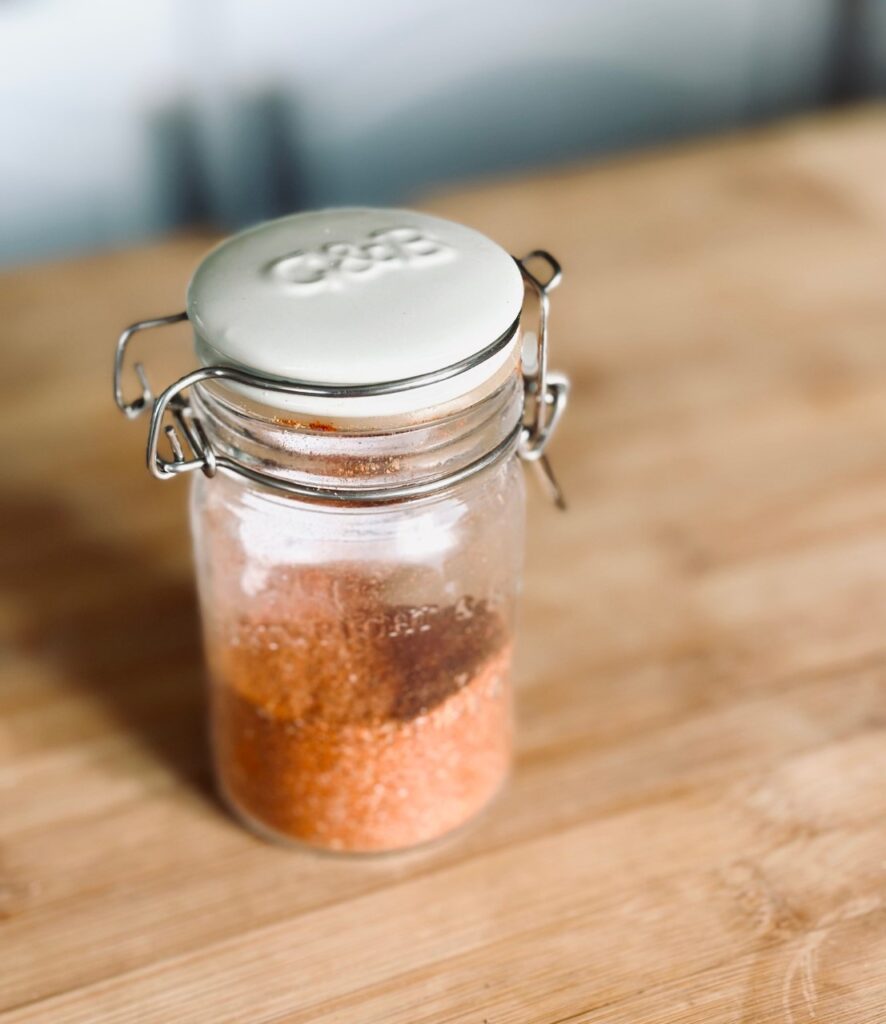 A flip top jar of seasoning on a wooden cutting board