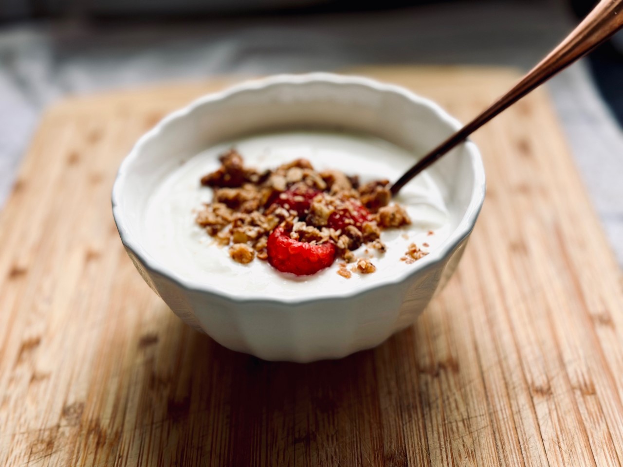 a bowl of yoghurt topped with granola and raspberries