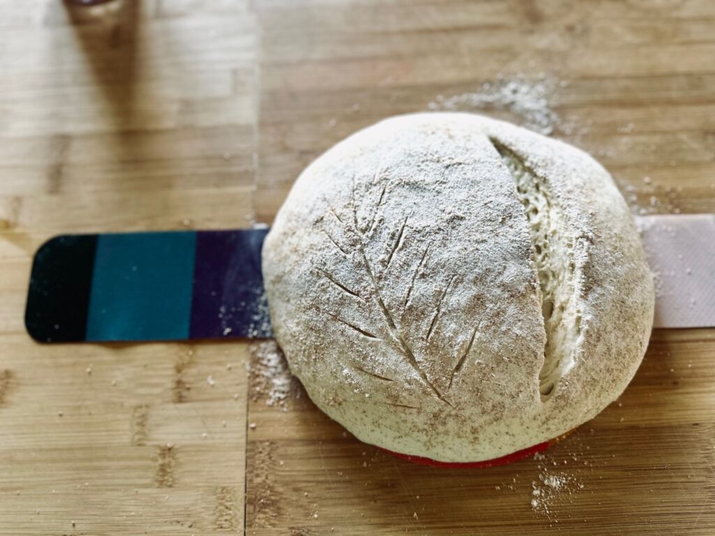 An unbaked loaf of scored sourdough bread on a work surface