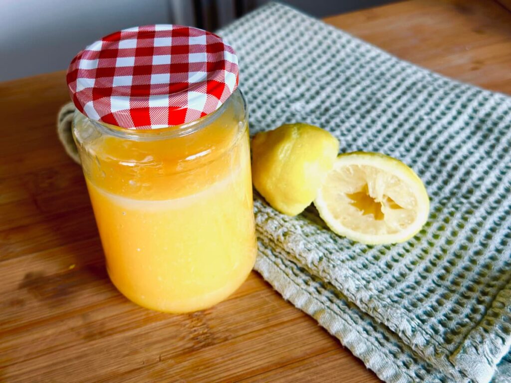 A jar of Lemon Curd next to some squeezed lemons