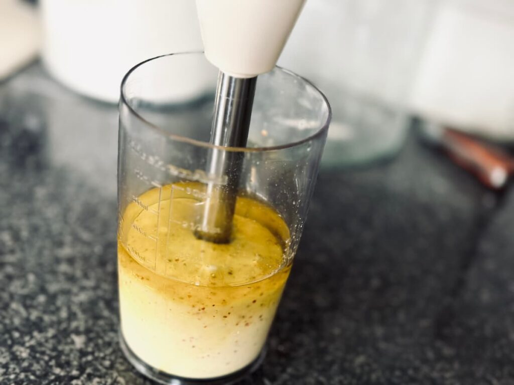 A measuring jug with the contents being blended with an immersion blender
