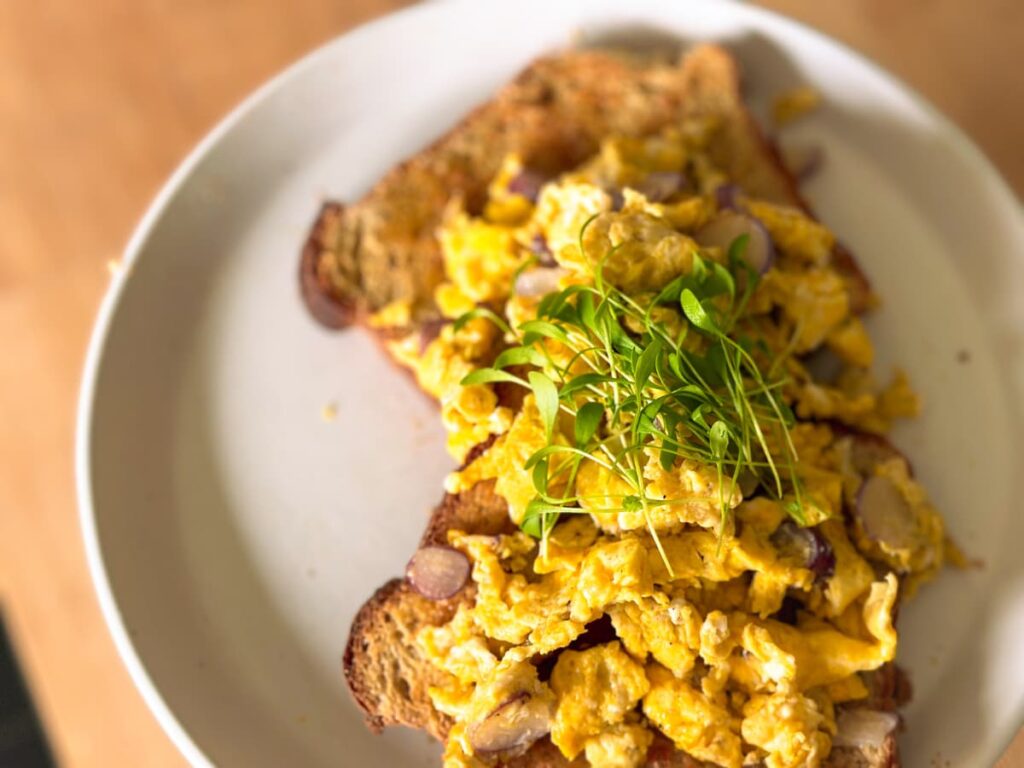 Egg on toast on a plate, topped with microgreens