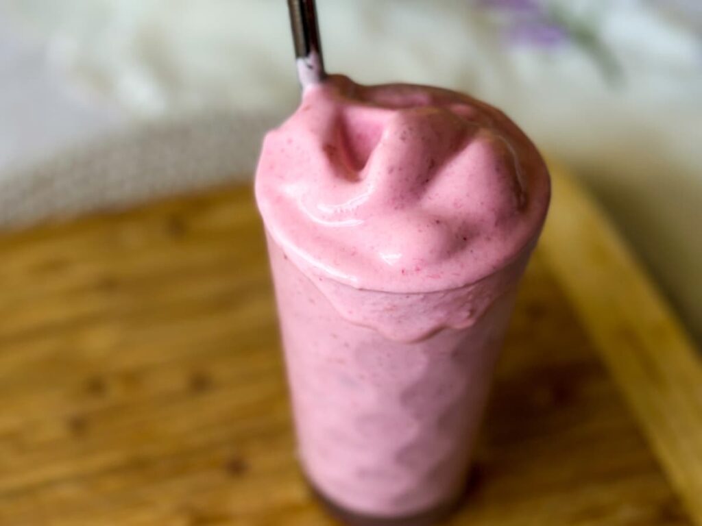 A glass of pink smoothie to show the top 3 delicious summer smoothie recipes 2023
