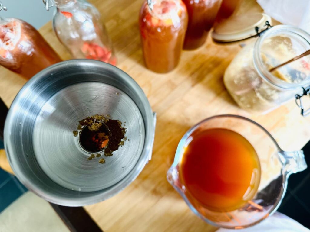 A jug of Kombucha, with a funnel containing sugar to carbonate the kombucha