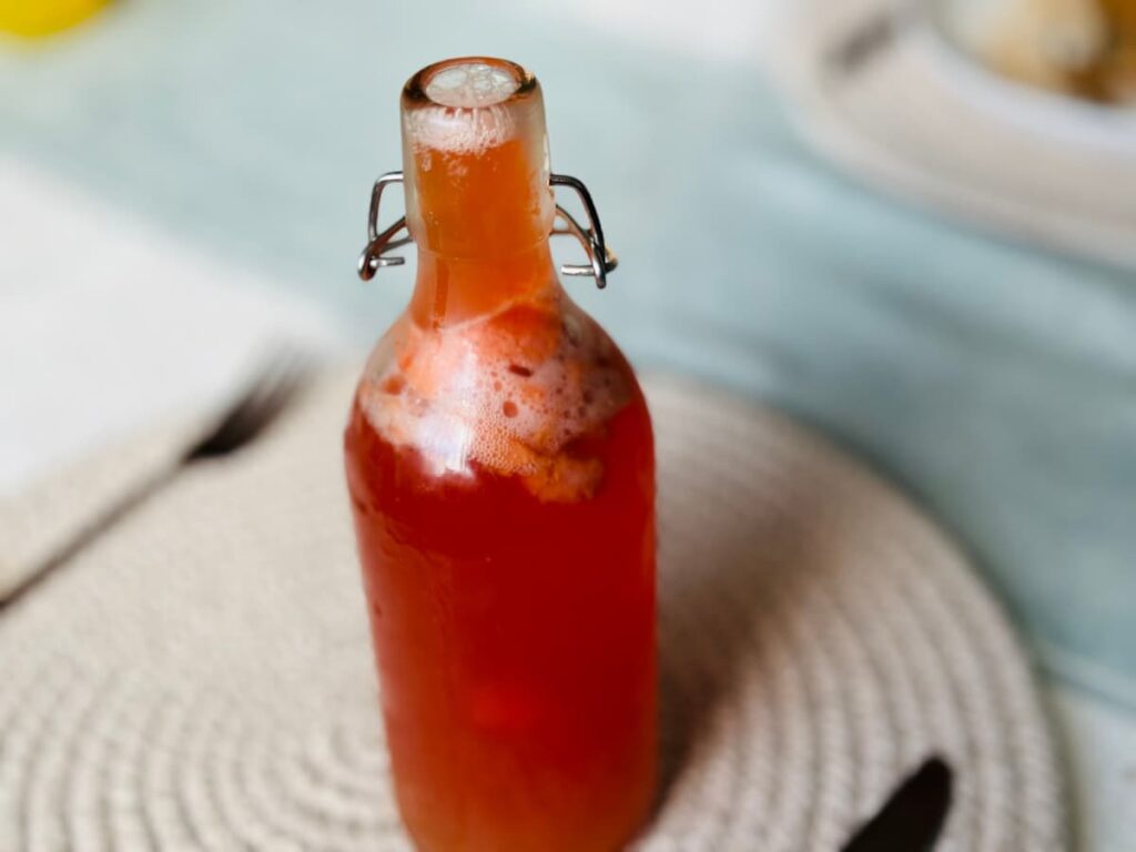 A fizzy bottle of Kombucha on a placemat