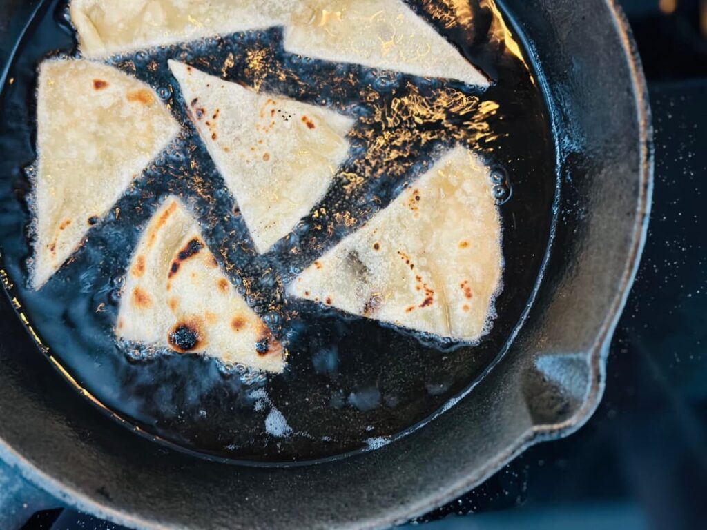 Tortilla wedges shallow frying in a cast iron pan
