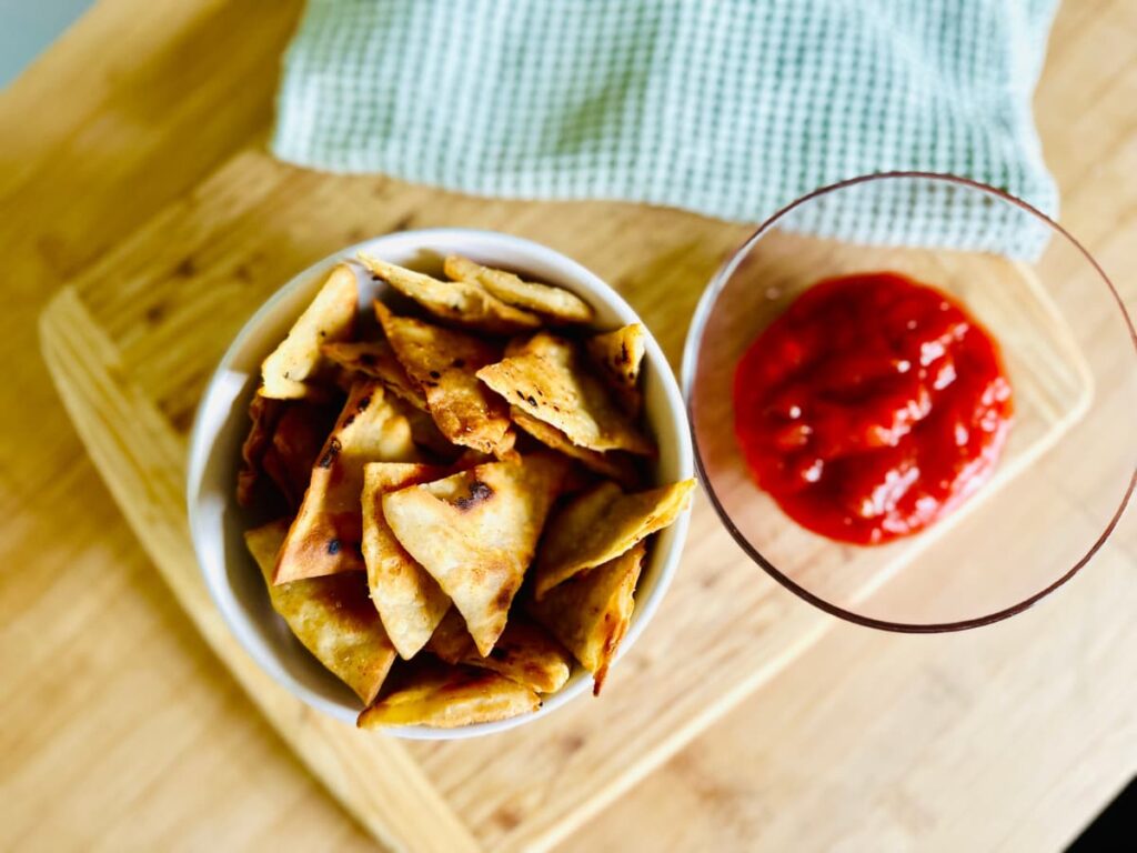 A bowl full of homemade Tortilla Chips next to a bowl of salsa