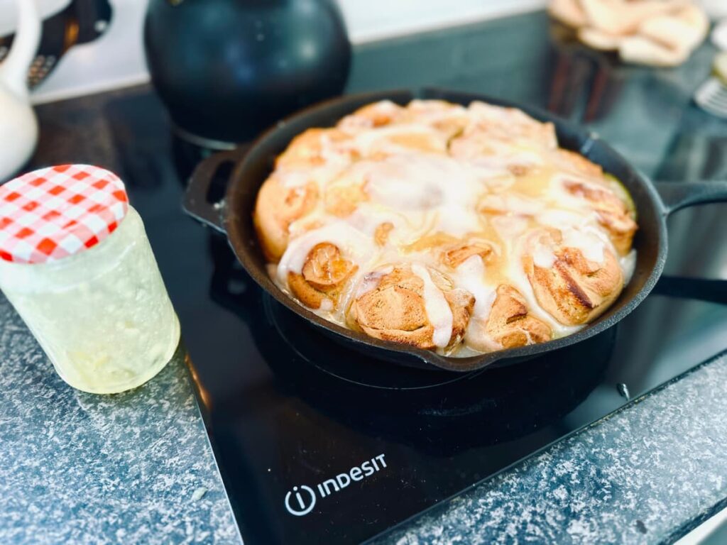 A cast iron pan filled with iced Sourdough Lemon Rolls