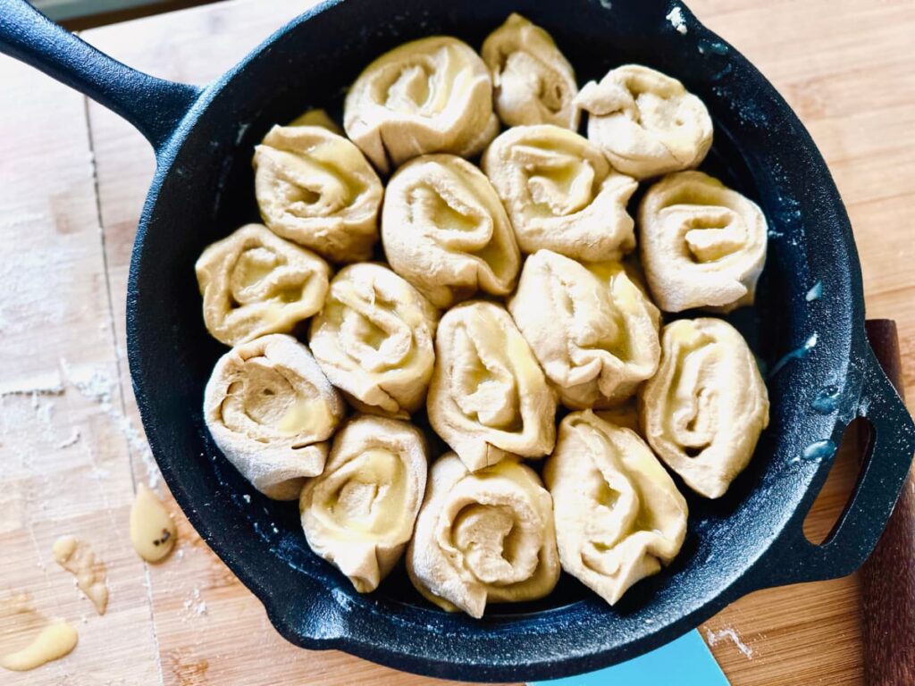 A cast iron pan filled with uncooked Sourdough lemon rolls