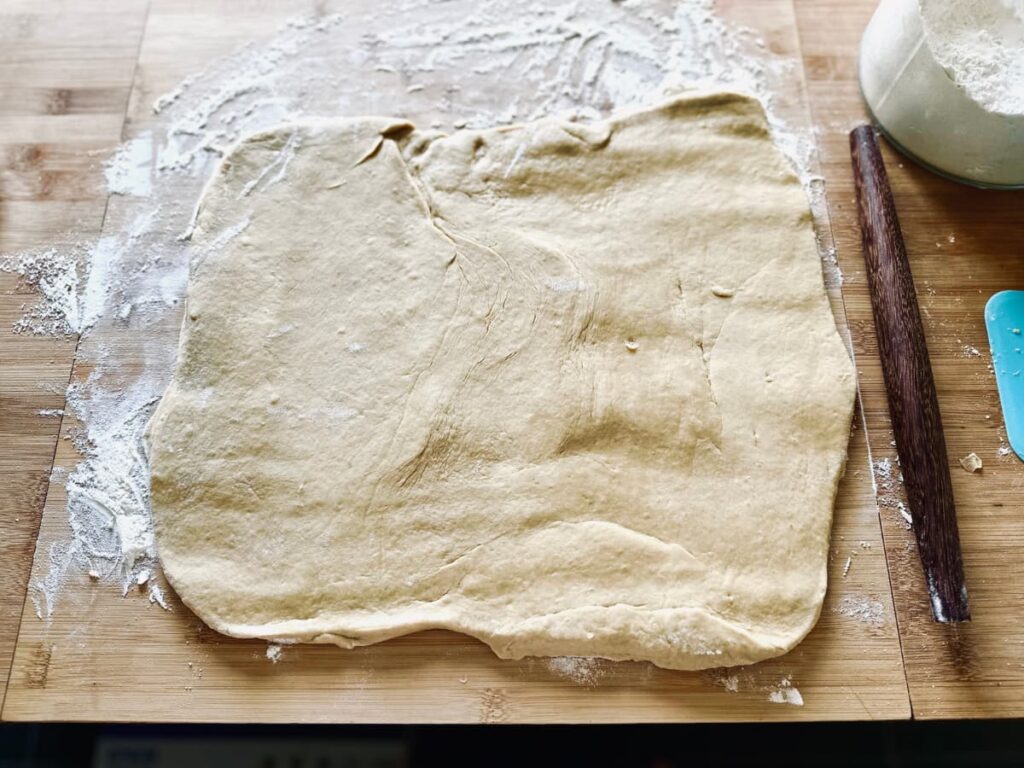 rolled out dough on a floured surface next to a rolling pin