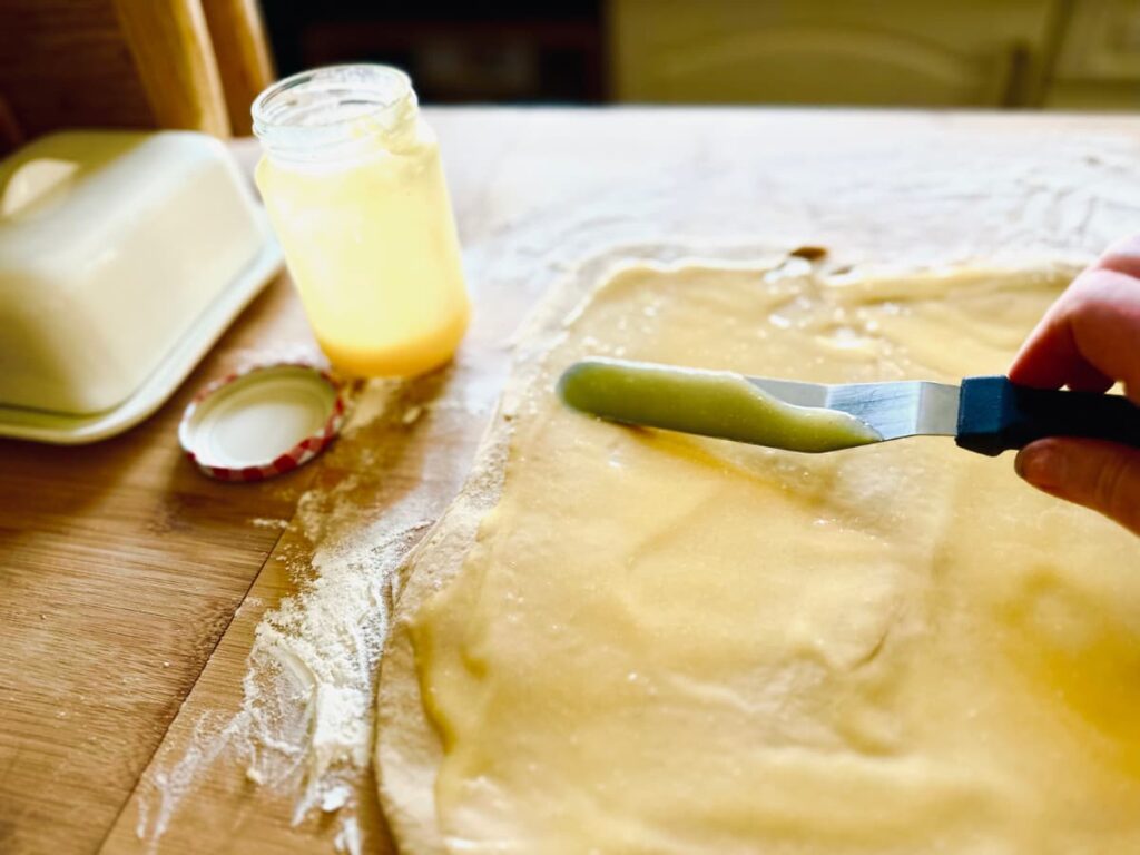 Spreading lemon curd over the rolled out dough
