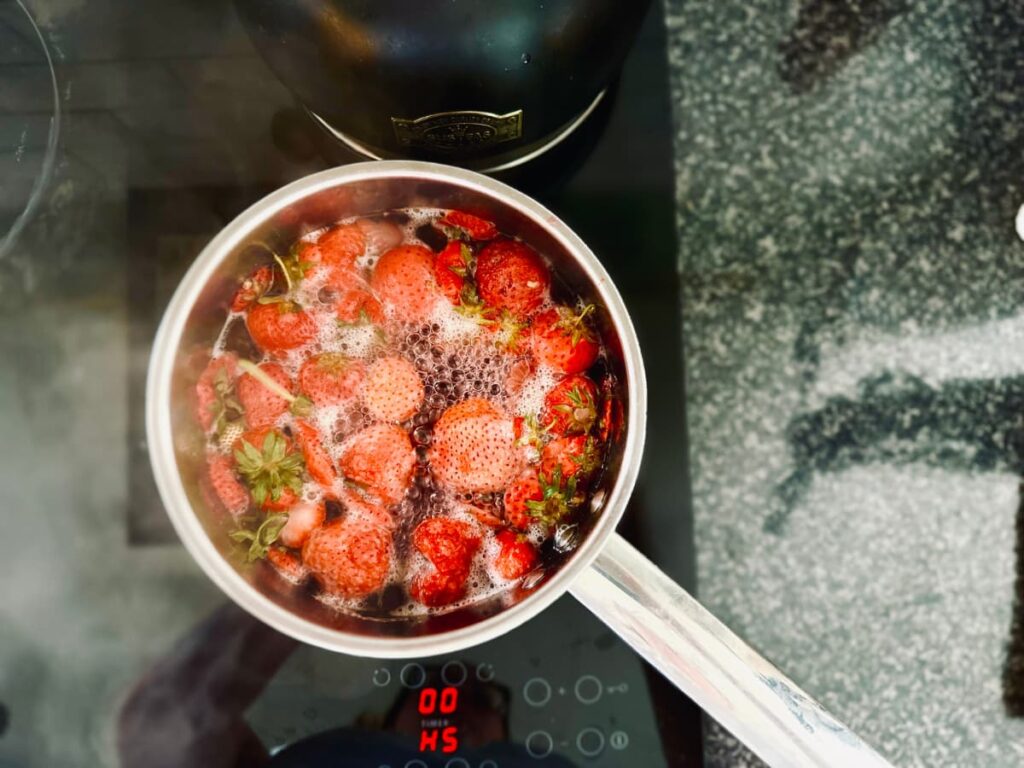 A saucepan full of boiling strawberry top syrup