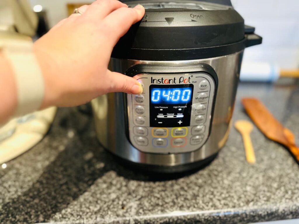 A hand activating a function on an instant pot