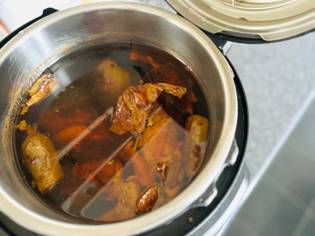 An Instant Pot full of stewed chicken bones and broth