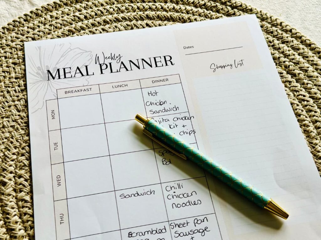 A partially completed meal plan on a woven place mat with a pen laid on top