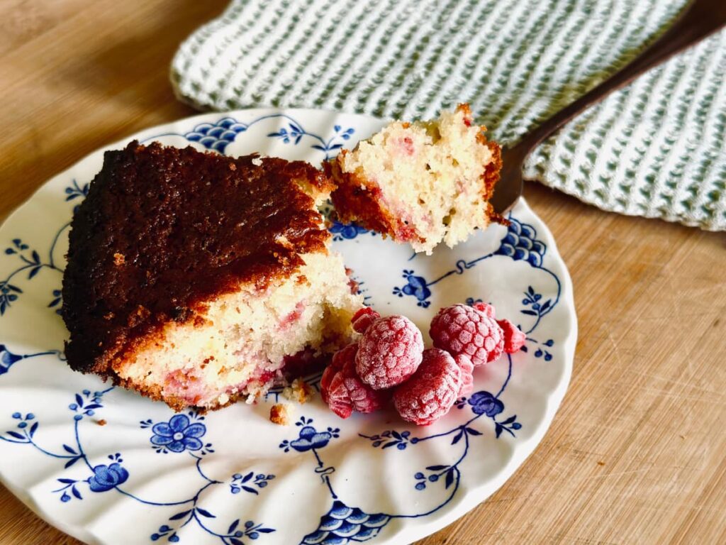 A slice of raspberry sourdough discard breakfast cake on a plate with a fork full next to it