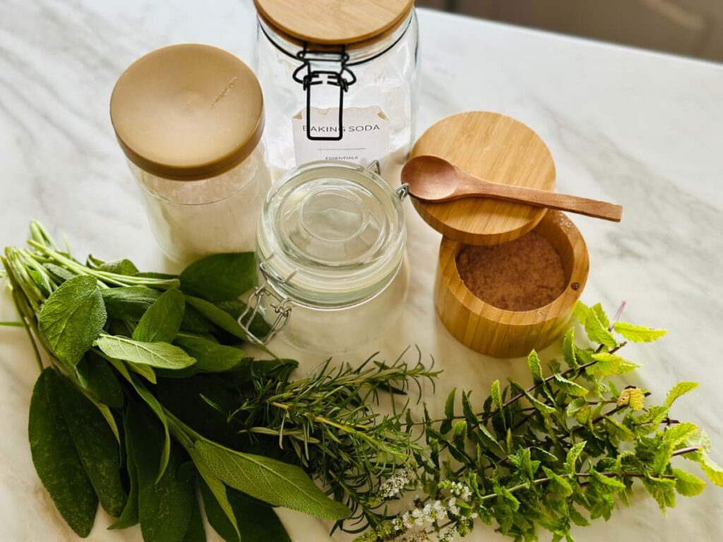 jars and containers arranged around fresh herbs to make Herbal bath salts