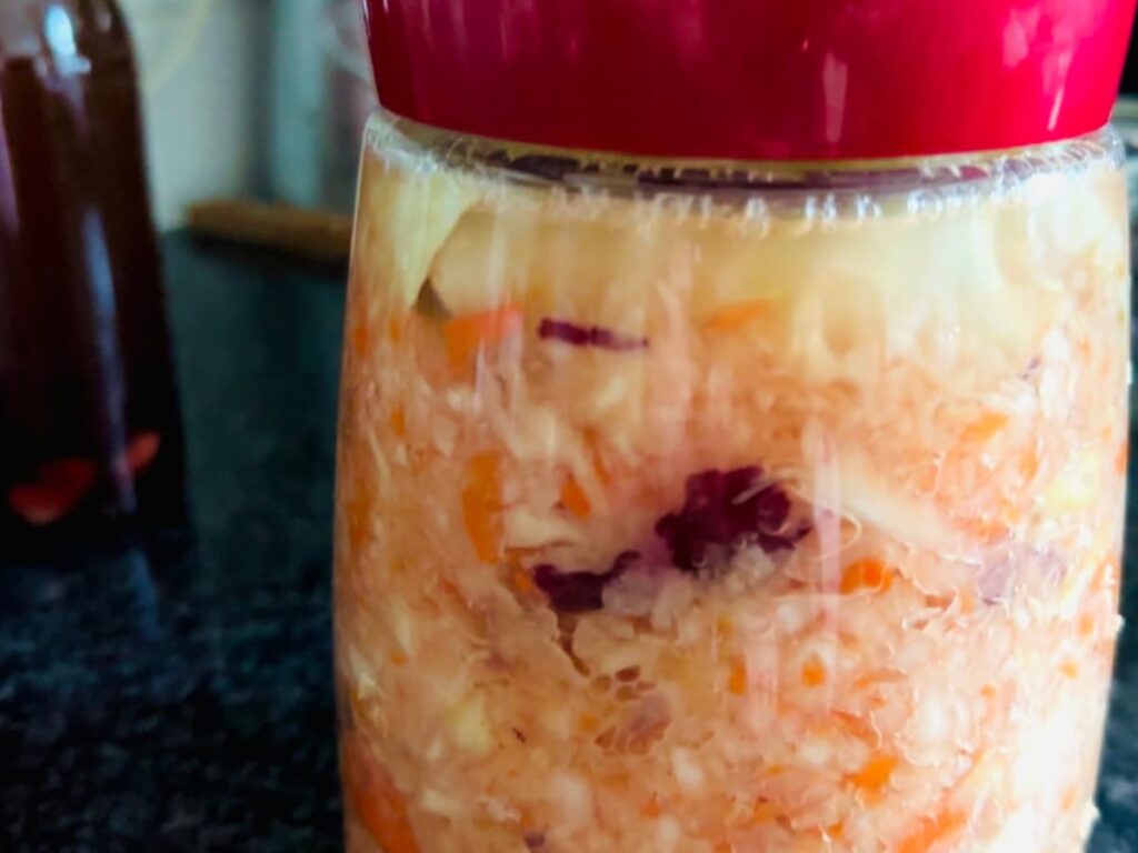 A bubbling jar of fermented vegetables showing homemade Cortido