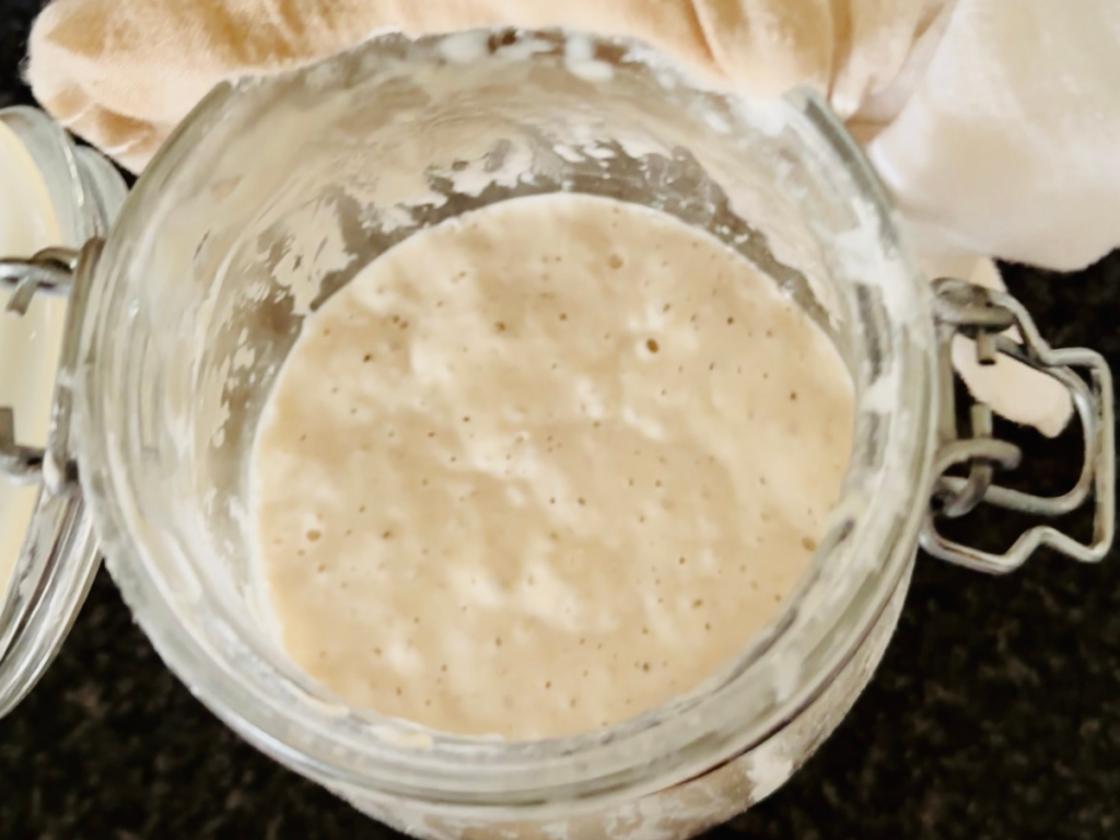 A top view of sourdough starter in a jar with bubbles
