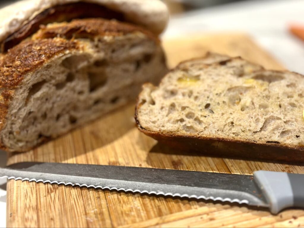Sliced Cheddar sourdough on a wooden chopping board with a knife
