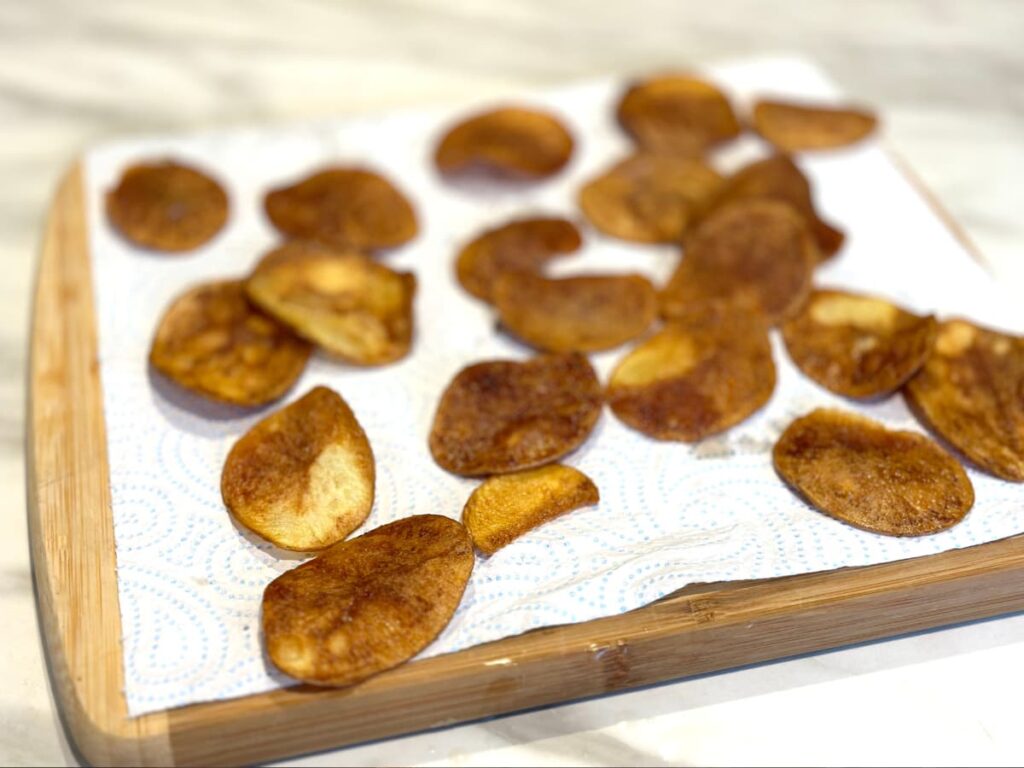 Potato chips colling on a board lined with paper towel
