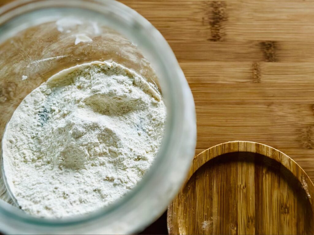 A close up of a glass jar of bread flour for sourdough starter